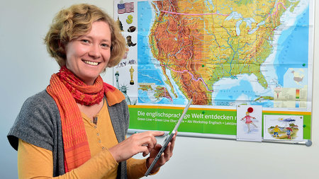 Frau steht vor einer Karte, auf welcher ein Ausschnitt Nordamerikas zu sehen ist