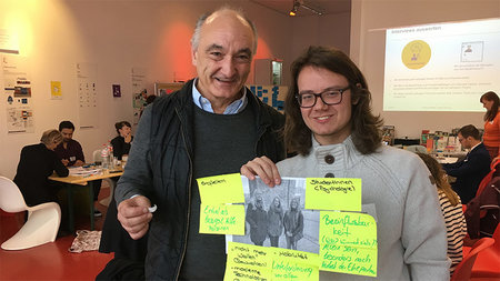 Zwei Teilnehmer der Impact Challenge zeigen ein Poster, über das diskutiert wurde.