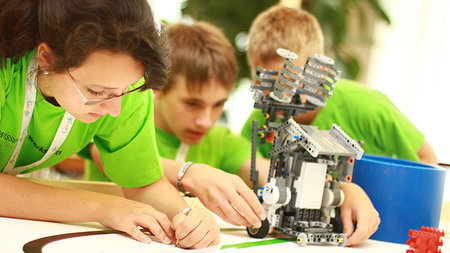 Drei Schüler bauen einen Roboter zusammen