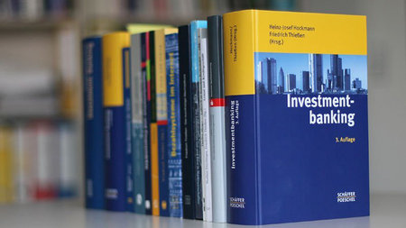 regal mit Büchern, im Vordergrund das Buch mit dem Titel "Investmentbanking".