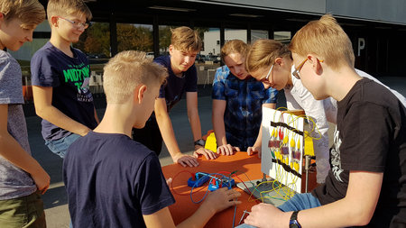 Mehrere Schüler experimentieren miteinander vor dem Physikgebäude