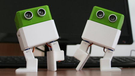 Zwei kleine Roboter tanzen auf einem Tisch