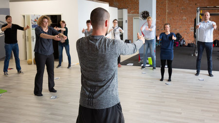 Mehrere Personen absolvieren eine sportliche Übung in einem Fitnessraum.