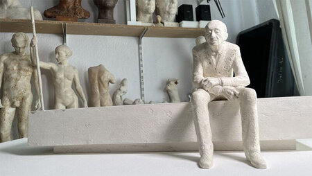 In einem Atelier ist ein Modell zu sehen, das einen auf einer Bank sitzenden Mann zeigt.