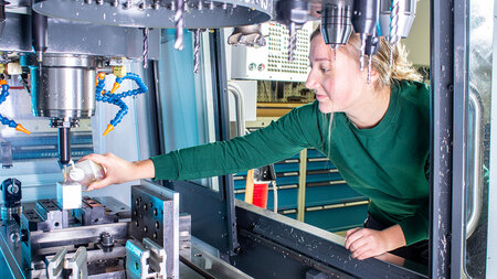 Eine junge Frau arbeitet an einer Werkzeugmaschine.