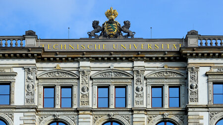 Teil einer historischen Gebäudefassade mit goldener Krone auf dem Dach und Schriftzug“技术大学”。