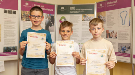 Drei Jungen halten Urkunden in den Händen.