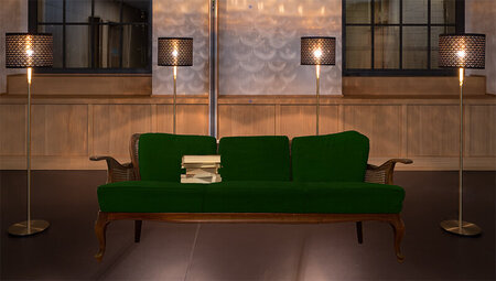 Grafik eines grünen Sofas, das vor einer beleuchteten Fenstefront steht.