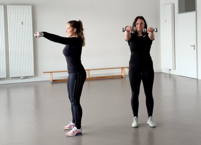 Frauen heben Hanteln auf Schulterhöhe