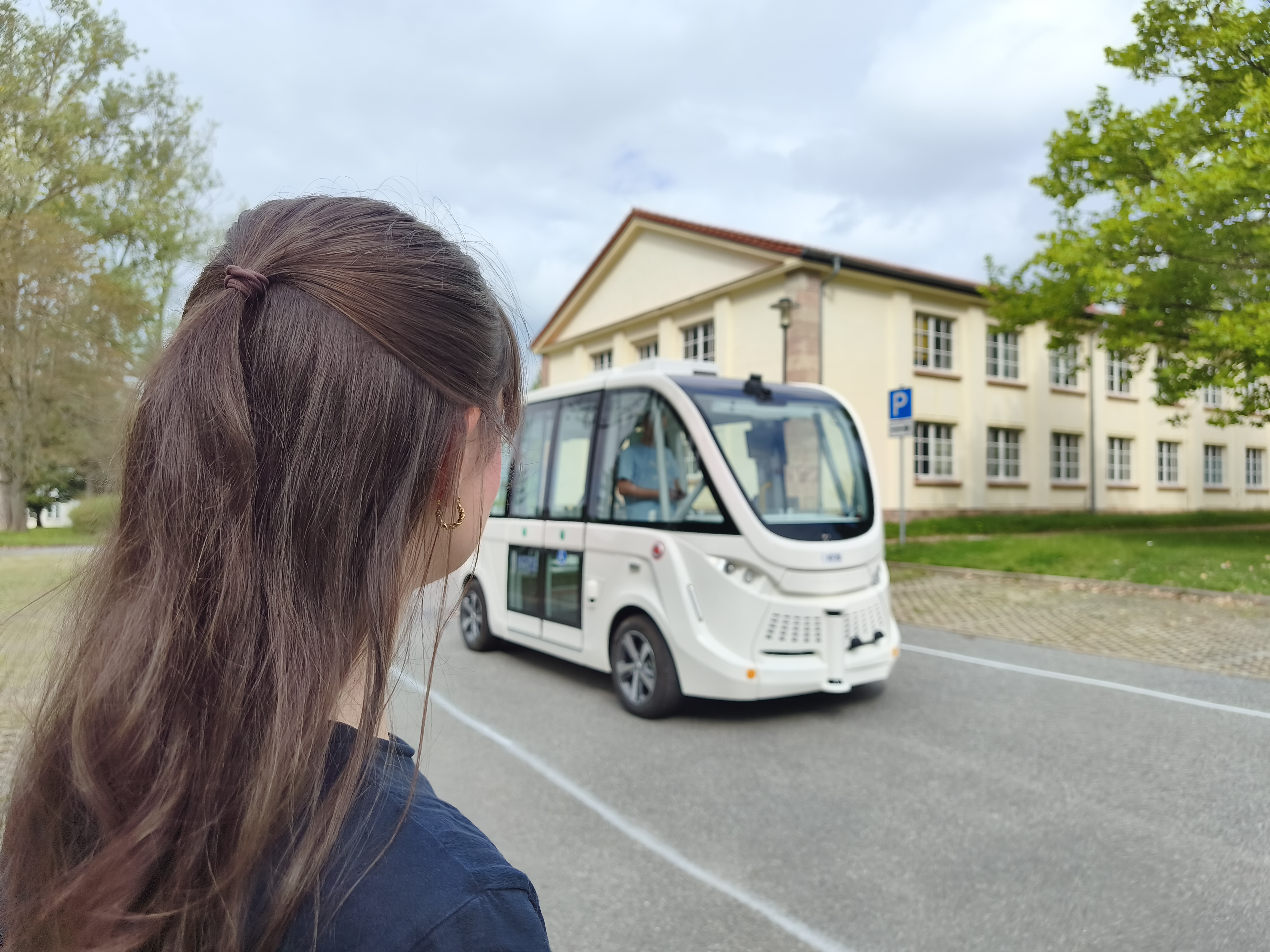 Fußgängerin die zu einem automatisierten Shuttle blickt