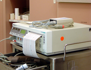 Bild eines Elektrokardiogramm-Geräts, welches ein EKG-Werte-Blatt ausdruckt.