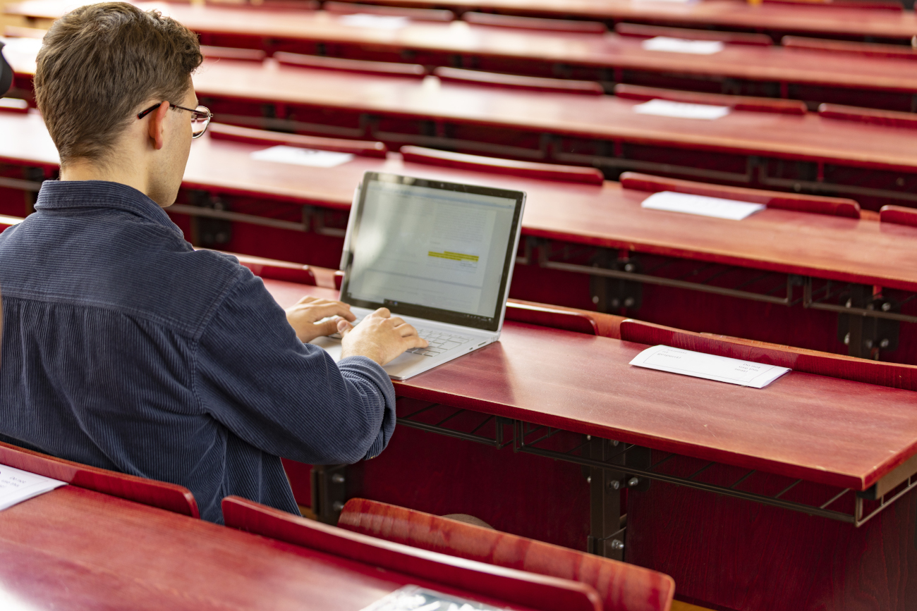 Ein junger Mann am Laptop im Hörsaal