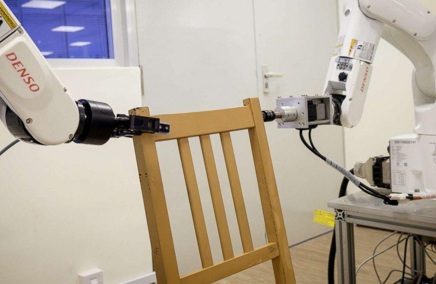 Image showing two industrial robots working together on a chair.