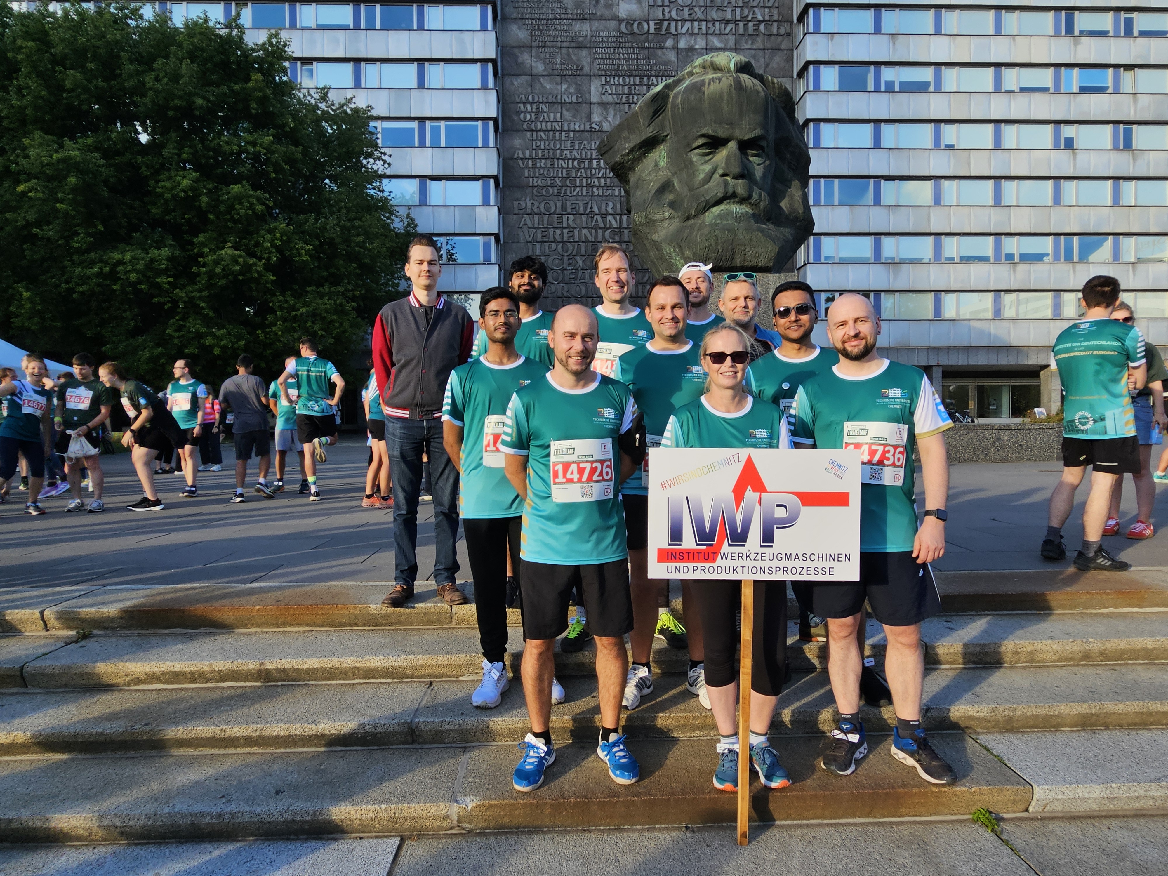 Gruppe von Menschen in Sportsachen steht hinter dem IWP-Schild