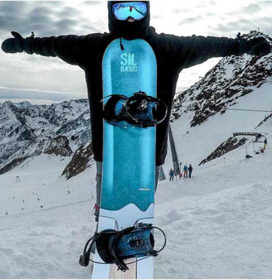 snowboarder auf Piste mit aufrecht stehendem Snowboard vor sich
