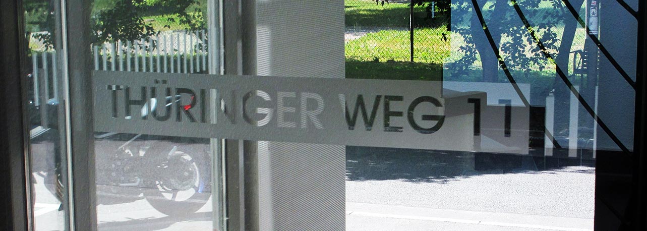 Aufschrift 'Thüringer Weg 12' an einer Glasfassade