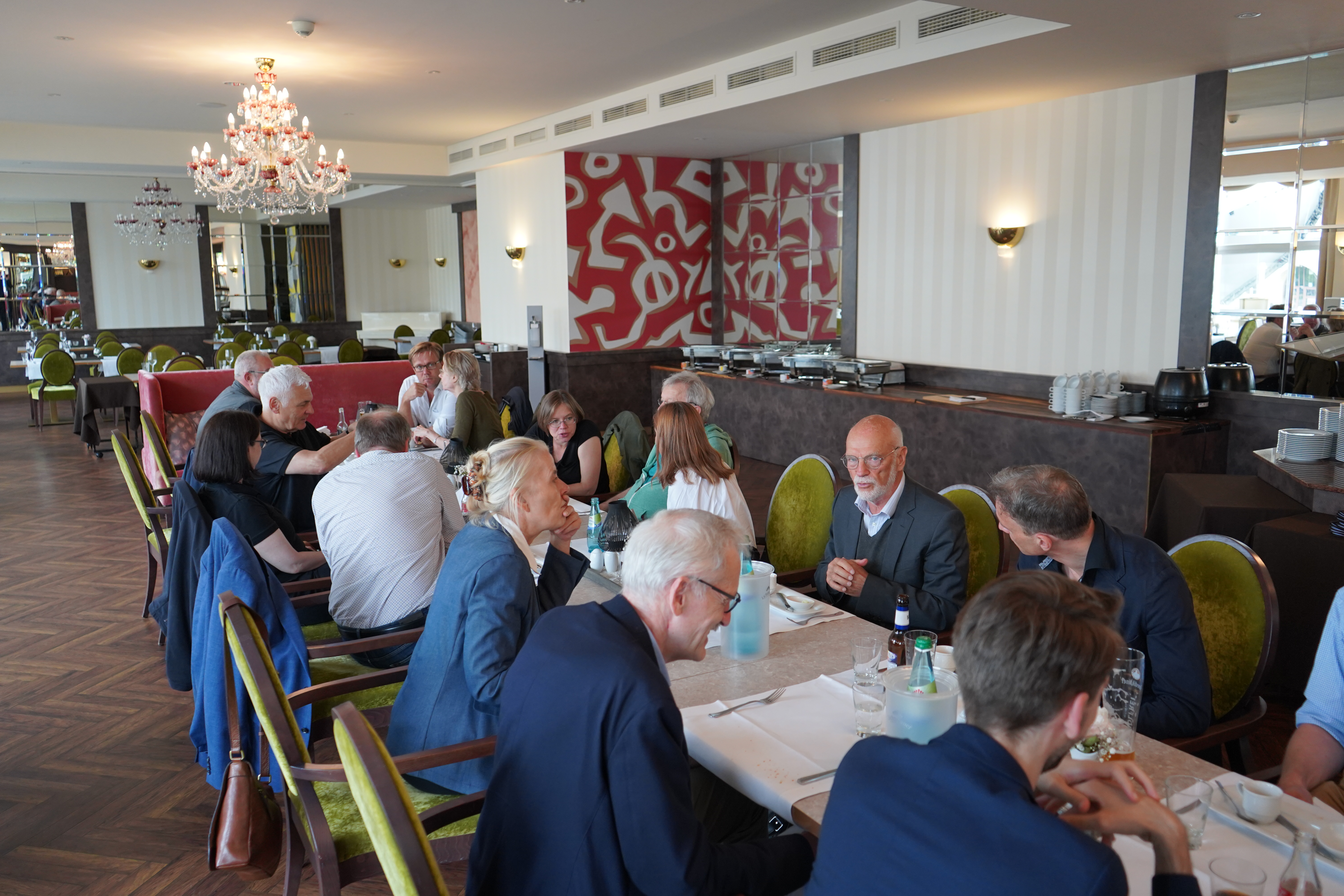Teilnehmer der Konferenz sitzen an einer langen Tafel beim gemeinsamen Mittagessen