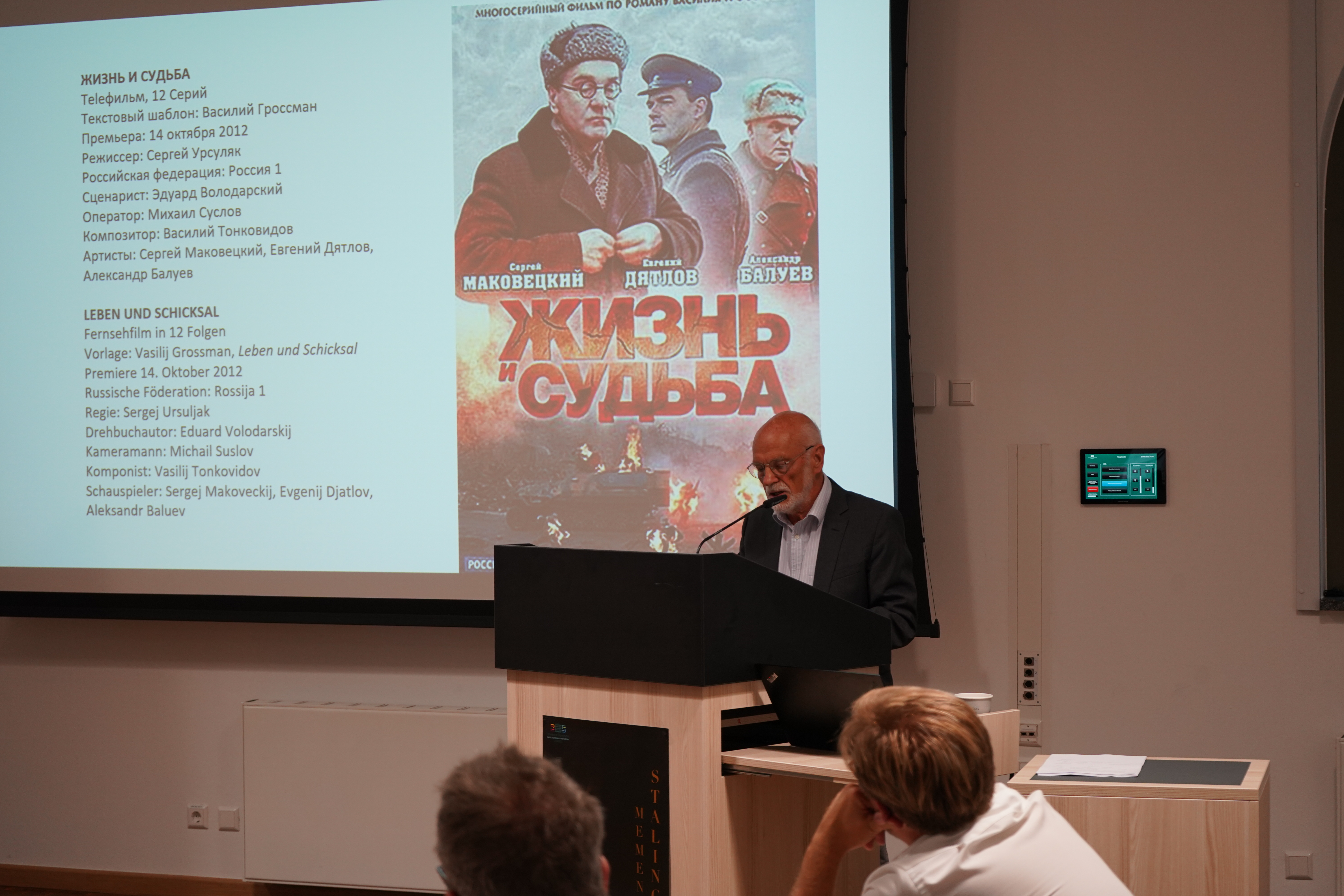 Professor Rainer Grübel referiert über Vasilij Grossmans Stalingrad-Roman: „Leben und Schicksal“; im Hintergrund auf der Leinwand ist ein Film-Cover zu sehen