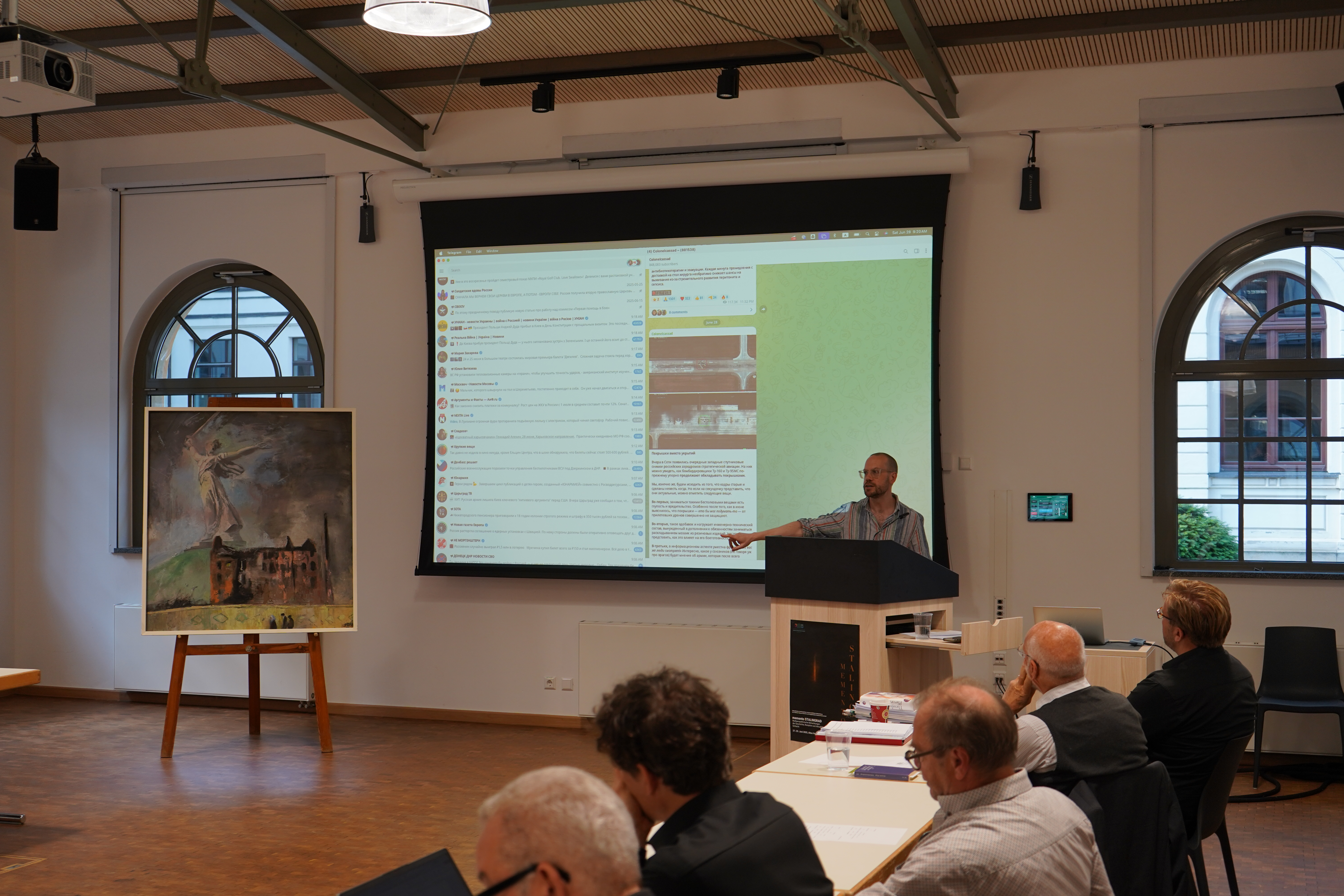 Prof. Dr. Ian Garner stellt die Ergebnisse seiner Datenerhebungen zu Stalingrad vor; im Hintergrund ist auf der Leinwand ein Telegram-Auszug zu sehen