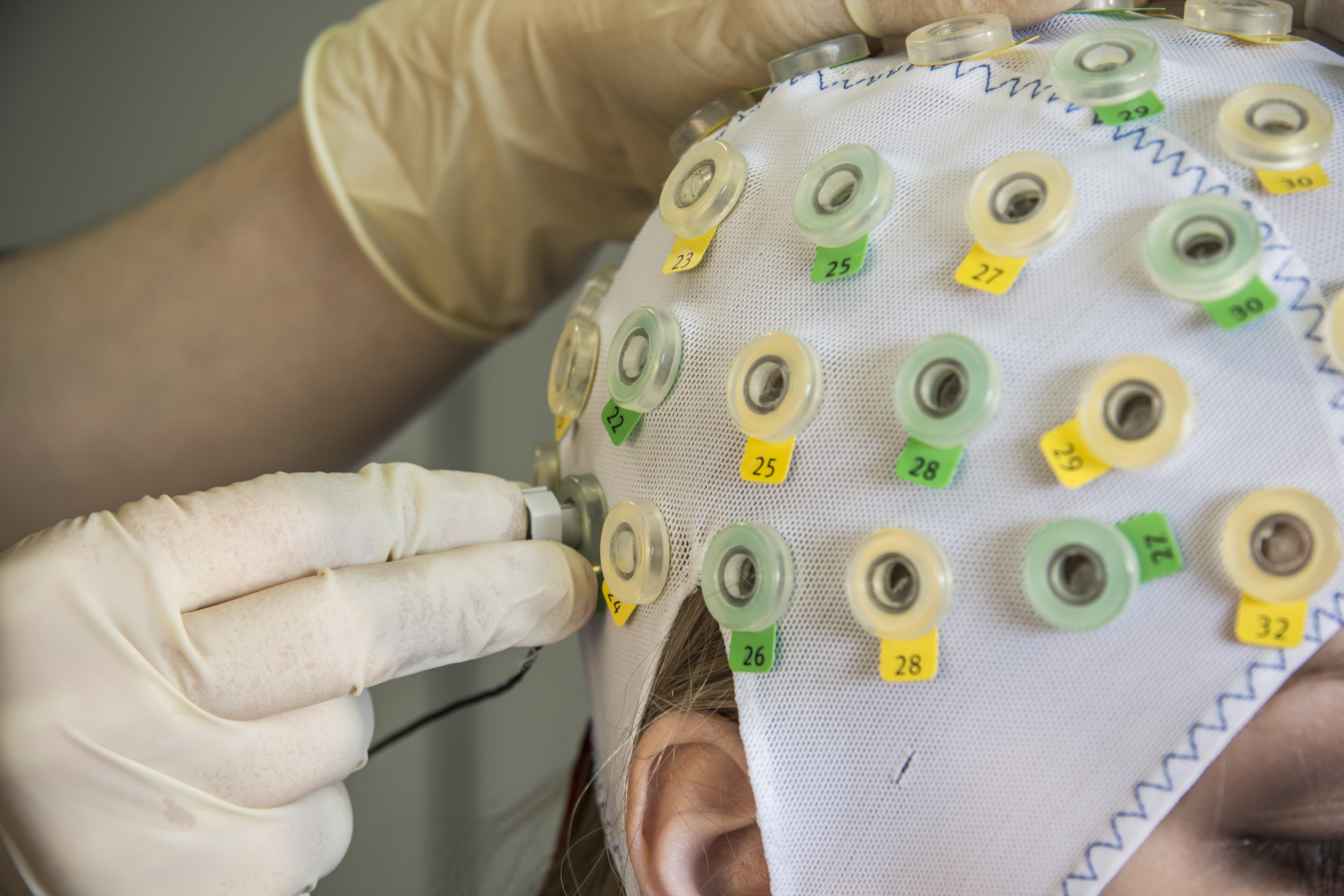 Anbringung der EEG-Elektroden an von Probandin getragener Haube