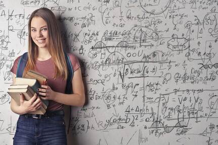 Junge Frau steht vor einer Wand mit mathematischen Formeln