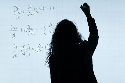 Junge Frau steht vor einer Wand mit mathematischen Formeln