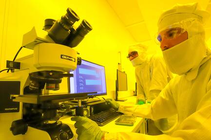 zwei Personen sitzen im Labor und arbeiten an einem Mikroskop