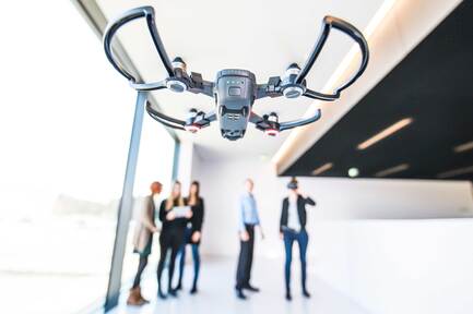 Fliegende Drohne mit Menschen im Hintergrund