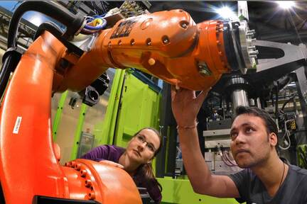zwei Personen arbeiten an einem Roboterarm