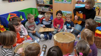 Kinder spielen in einem Raum im Kreis sitzend miteinander.