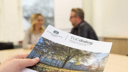 Eine Hand hält die erste Ausgabe von „TUCdialog“