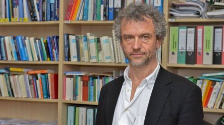 Prof. Dr. Peter Sedlmeier steht vor einem Bücherregal.