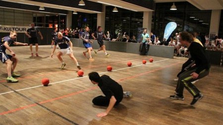 Zwei Teams spielen im großen Saal der Mensa gegeneinander Dodgeball.