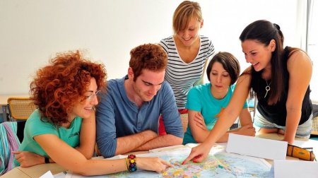 Internationale Studierende zeigen auf einer Weltkarte auf Europa.