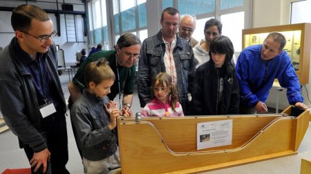 Besucher der Mitmachausstellung experimentieren an einer Kugelbahn.