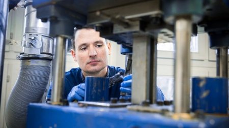 Junger Mann schaut auf ein Werkstück.