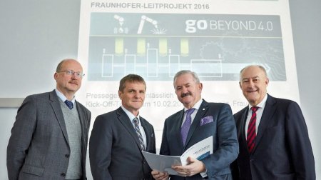 Vier Männer stehen vor einer Leinwand. Darauf zu lesen "Go Beyond 4.0"