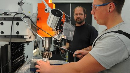 Ein Auszubildender bearbeitet in der Lehrwerkstatt an einer Fräsmaschine ein Werkstück.