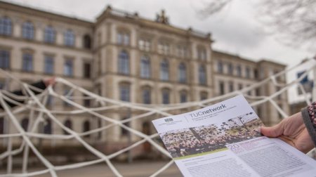 Die erste Ausgabe des Newsletters vor einem Netz, das vor dem TU-Hauptgebäude aufgespannt ist. 