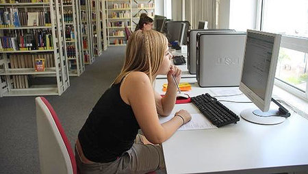 Eine Schülerin recherchiert in der Universitätsbibliothek an einem Computer.