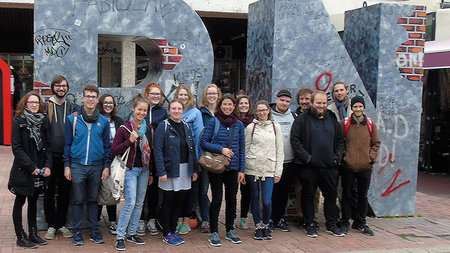 Exkursionsteilnehmerinnen und -teilnehmer vor dem NEWBORN-Monument im Herzen Prištinas.