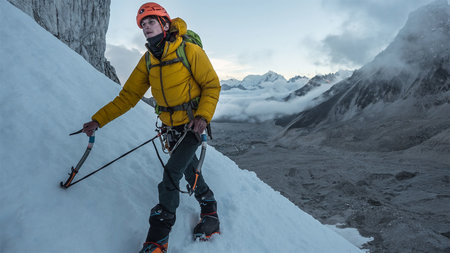 Ein Mann besteigt in einem Gebirge einen schneebedeckten Berg