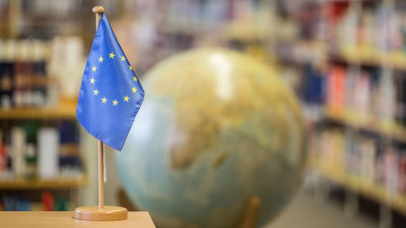 Bild aus einer Bibliothek mit der europäischen Flagge im Vordergrund und einem Globus im Hintergrund