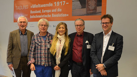 Gruppenfoto vor einem Plakat mit der Aufschrift "Weltwende 1917"