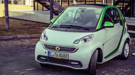 Ein E-Smart steht vor einem TU-Gebäude.