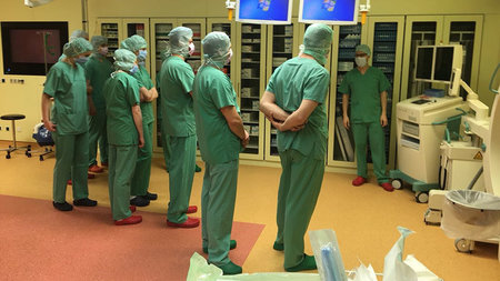 Studierende und Ärzte stehen in Schutzkleidung im Hybrid-Operationssaal