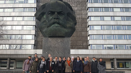 Gruppe von Menschen steht vor dem Marx-Monument in Chemnitz.
