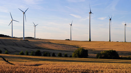 Mehrere Windräder stehen auf einem Feld.