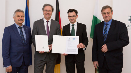 Die Vertreter der TU Chemnitz und der IHK Chemnitz halten den unterzeichneten Vertrag hoch.