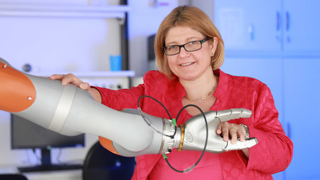Prof. Dr. Ulrike Thomas hält einen Roboterarm fest.